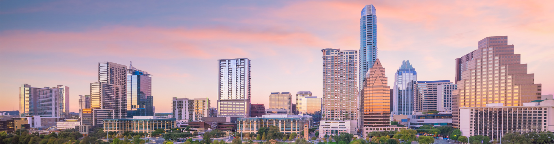 A city skyline with a pink and purple sky.