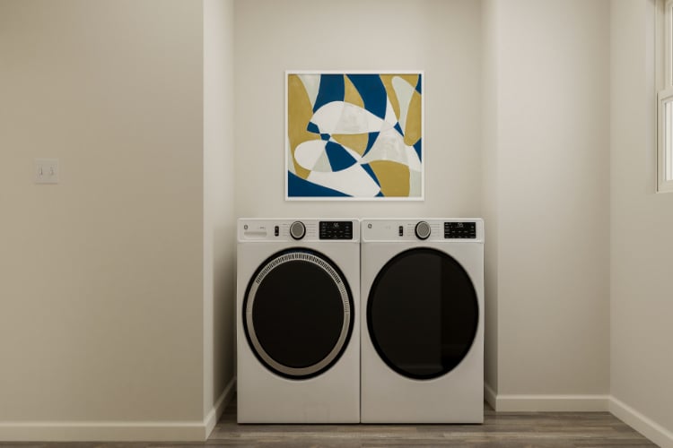 A white wall with a picture of a laundry basket and a painting on it.