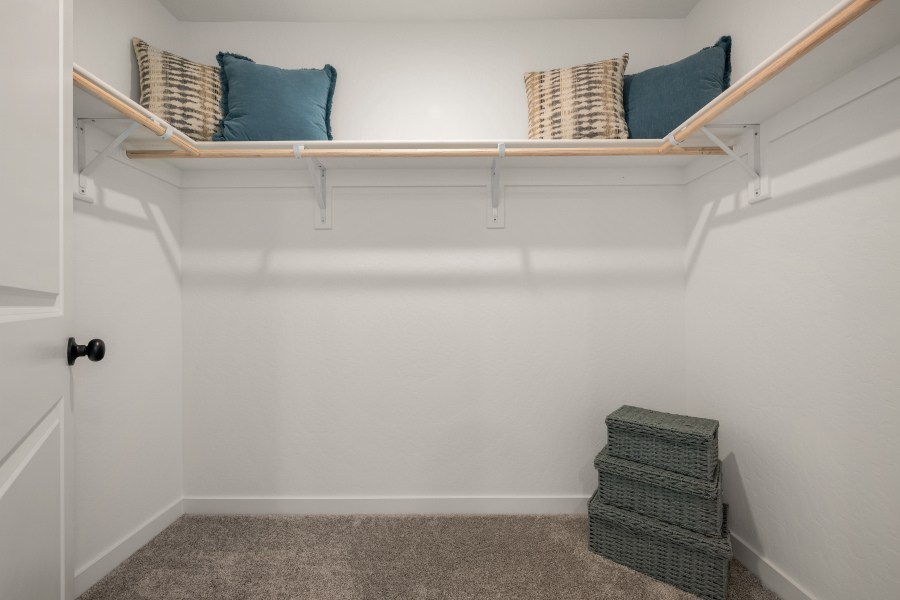 A shelf with baskets and pillows.