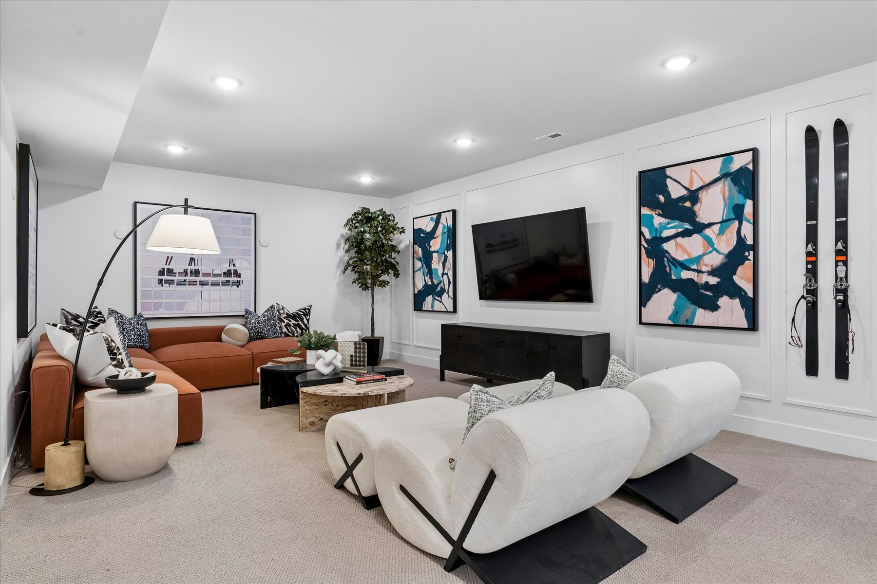 A living room with a white couch and a white wall with art.