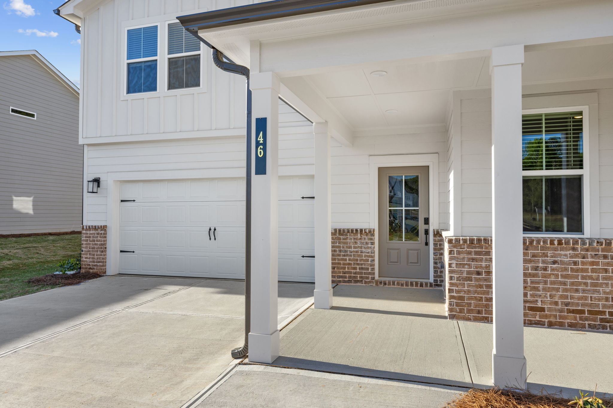 A white garage with a brick driveway.