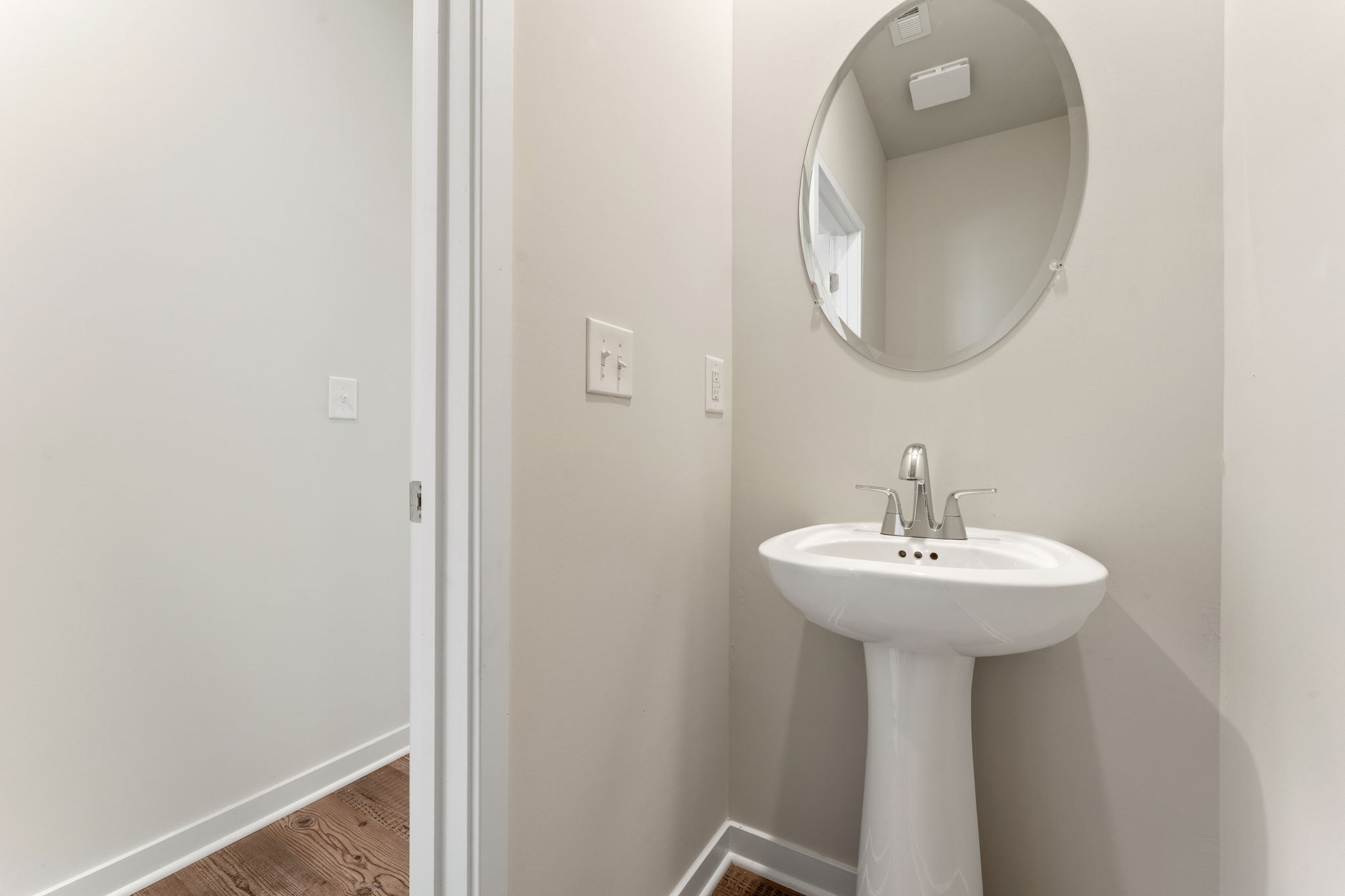 A bathroom with a round mirror.