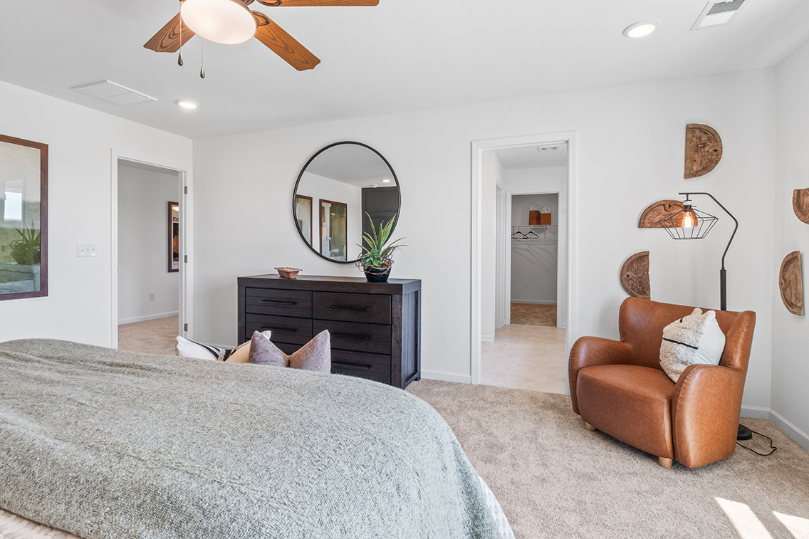 A bedroom with a bed and a chair.