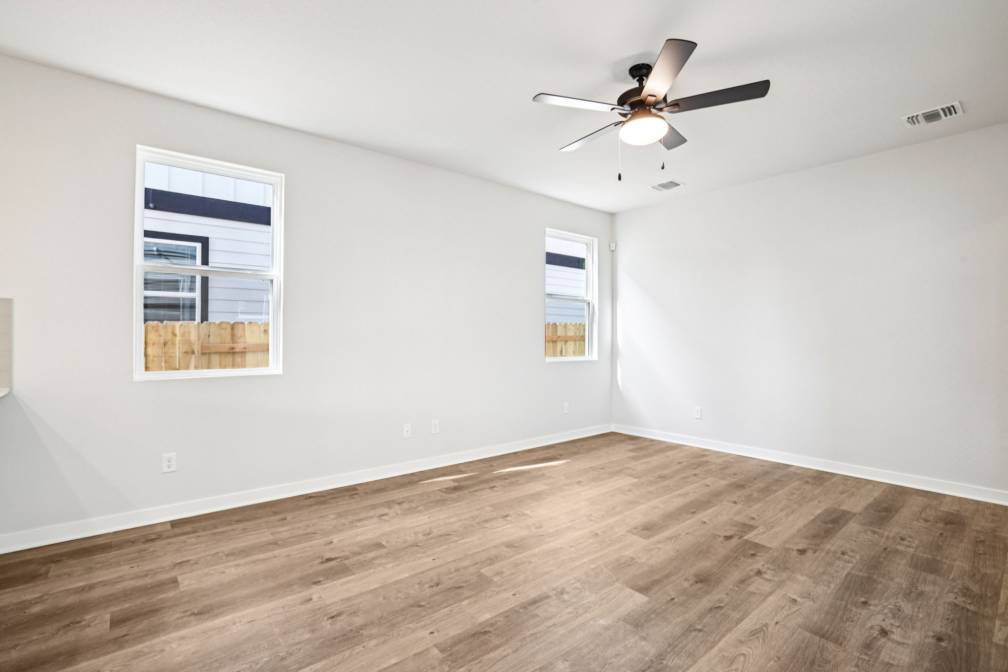 A room with a ceiling fan and a wood floor.