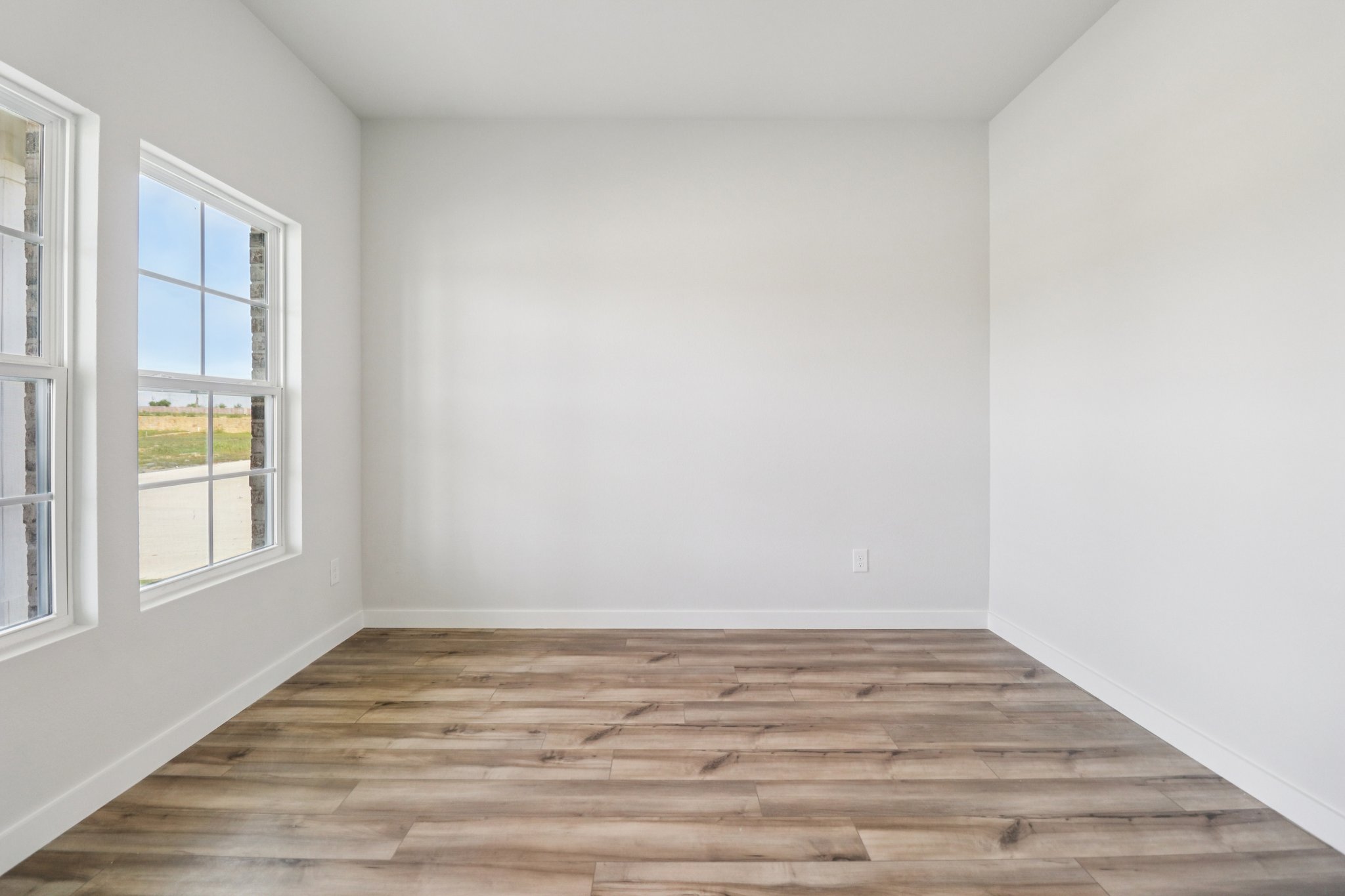 A room with a wood floor and windows.