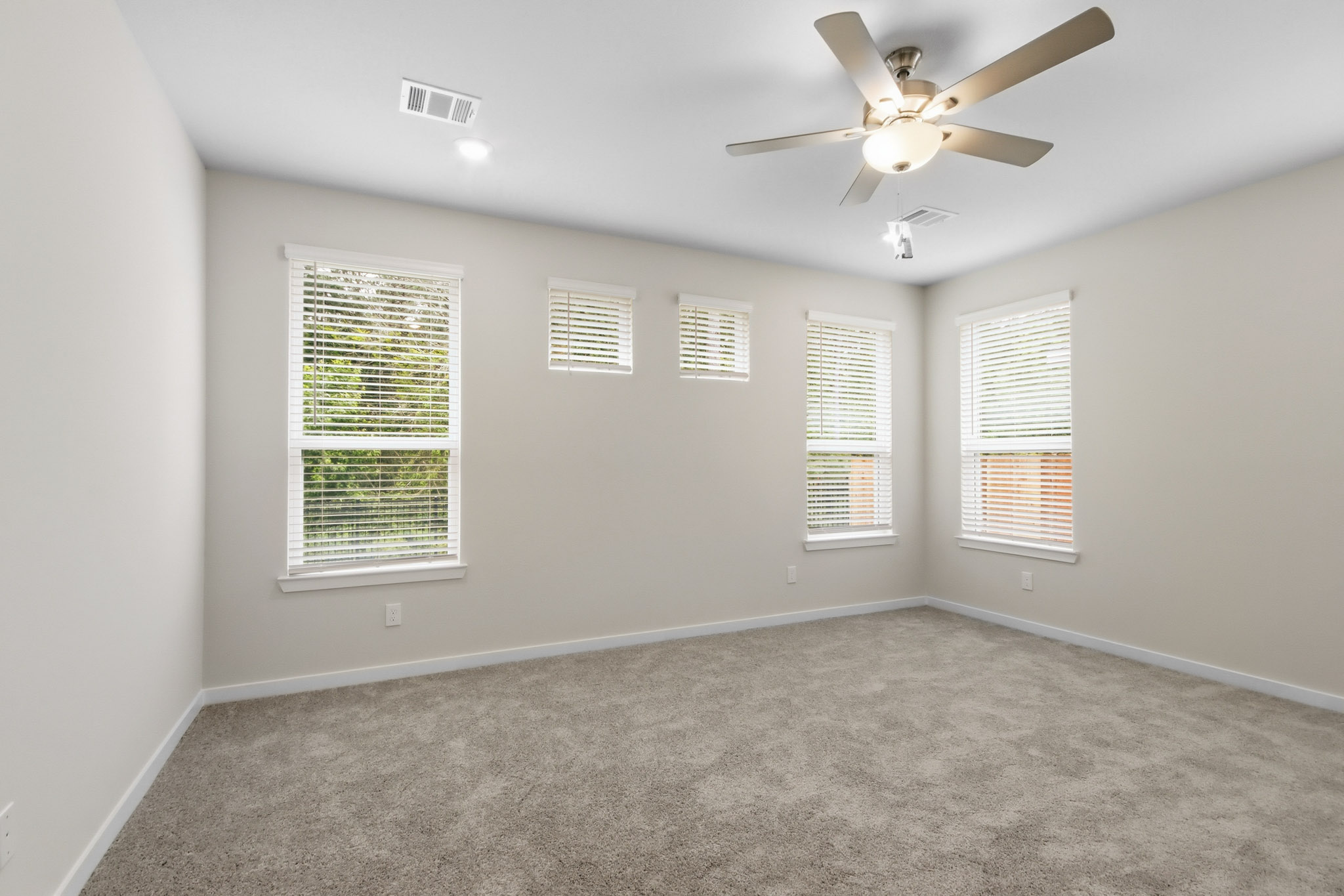 A room with a ceiling fan and a carpet.