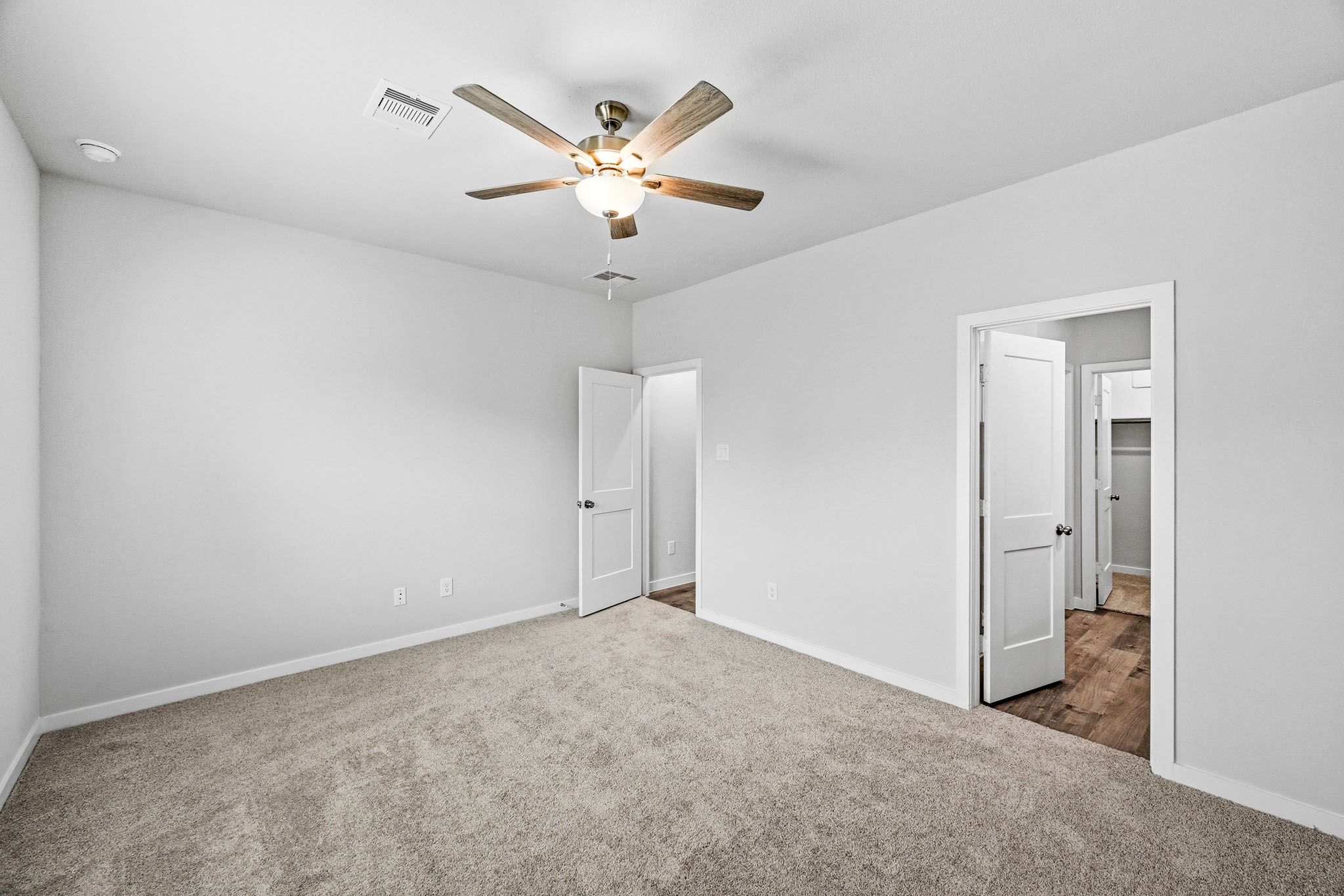 A room with a ceiling fan and white walls.