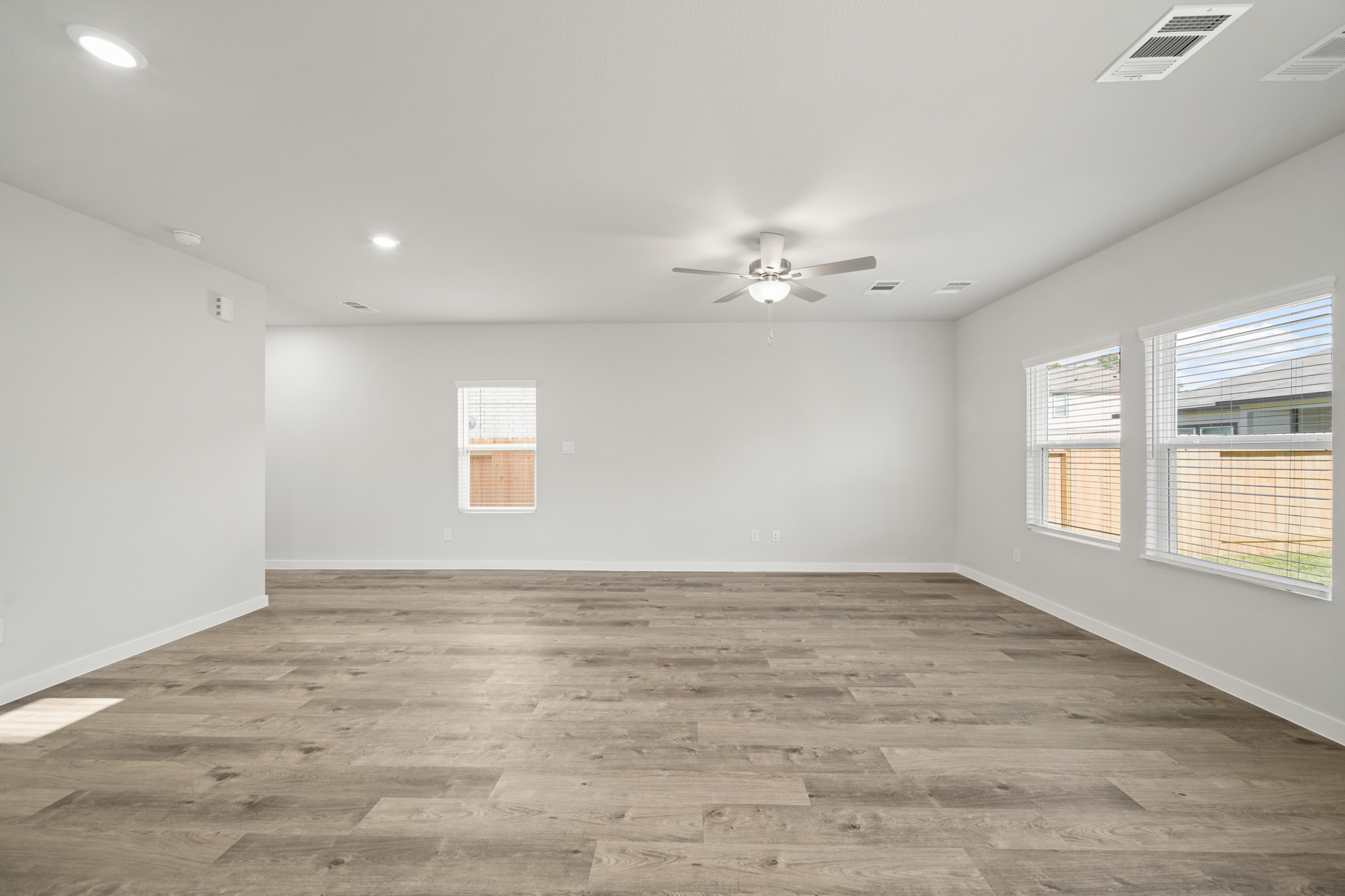 A room with a ceiling fan and a wood floor.