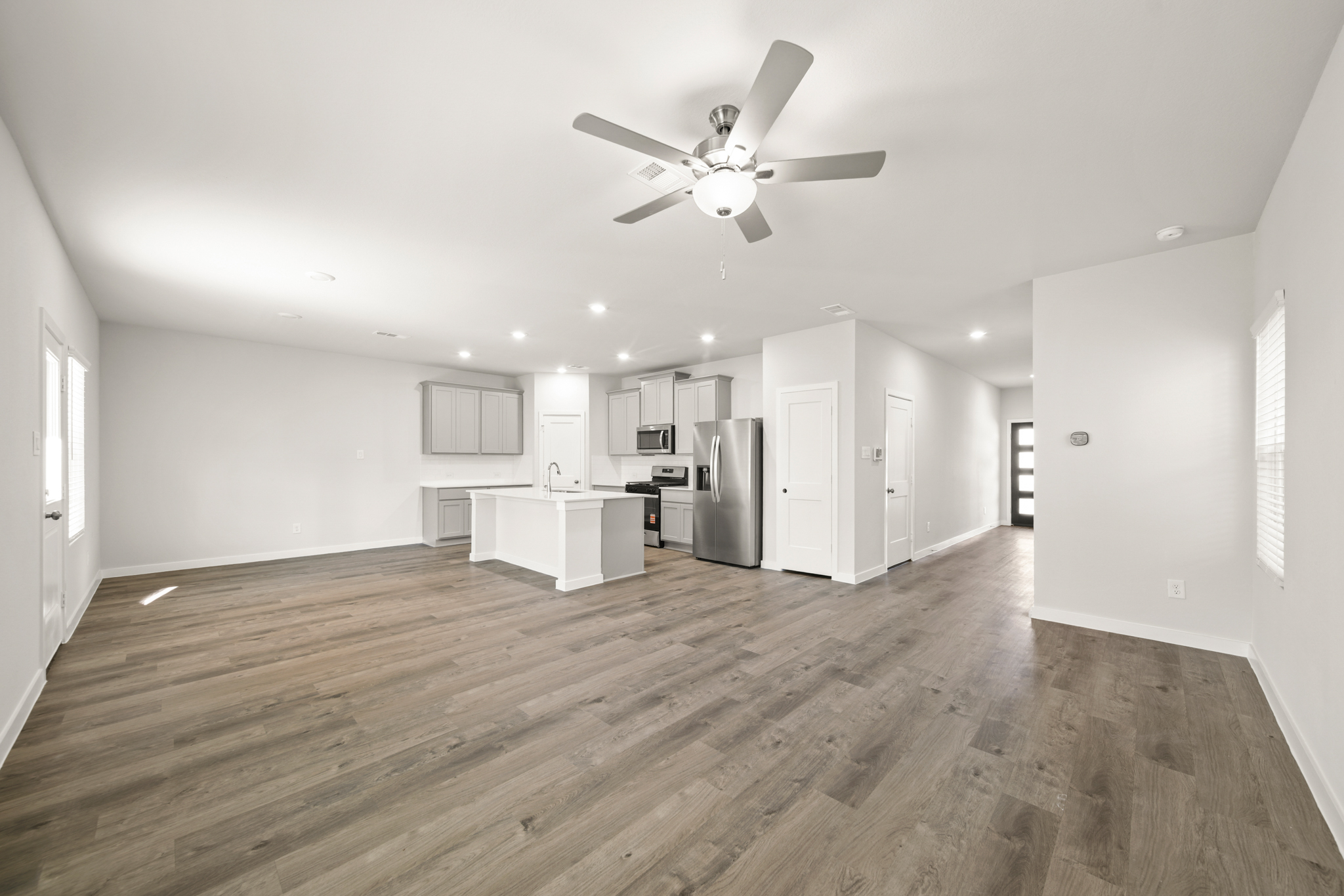 A large empty room with a ceiling fan and a wood floor.