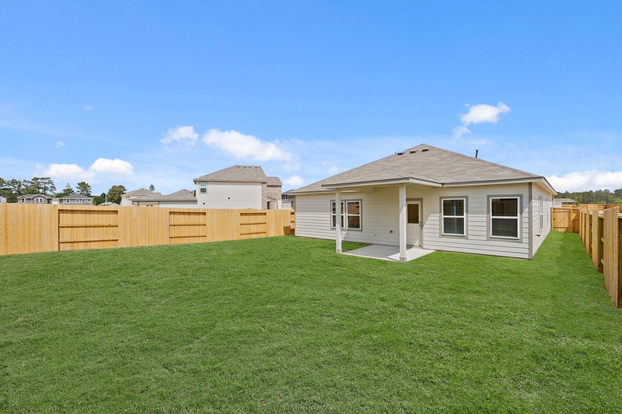A grassy yard with a fence and a house in the background.