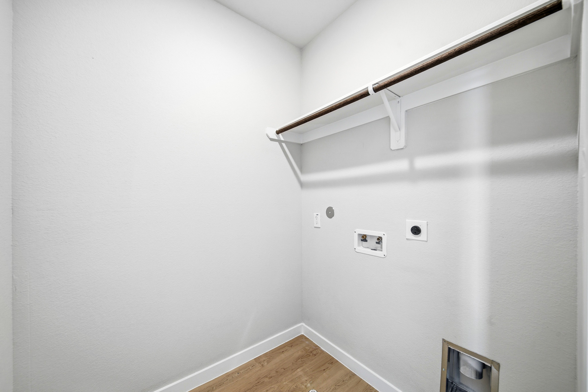 A white wall with a wood floor.