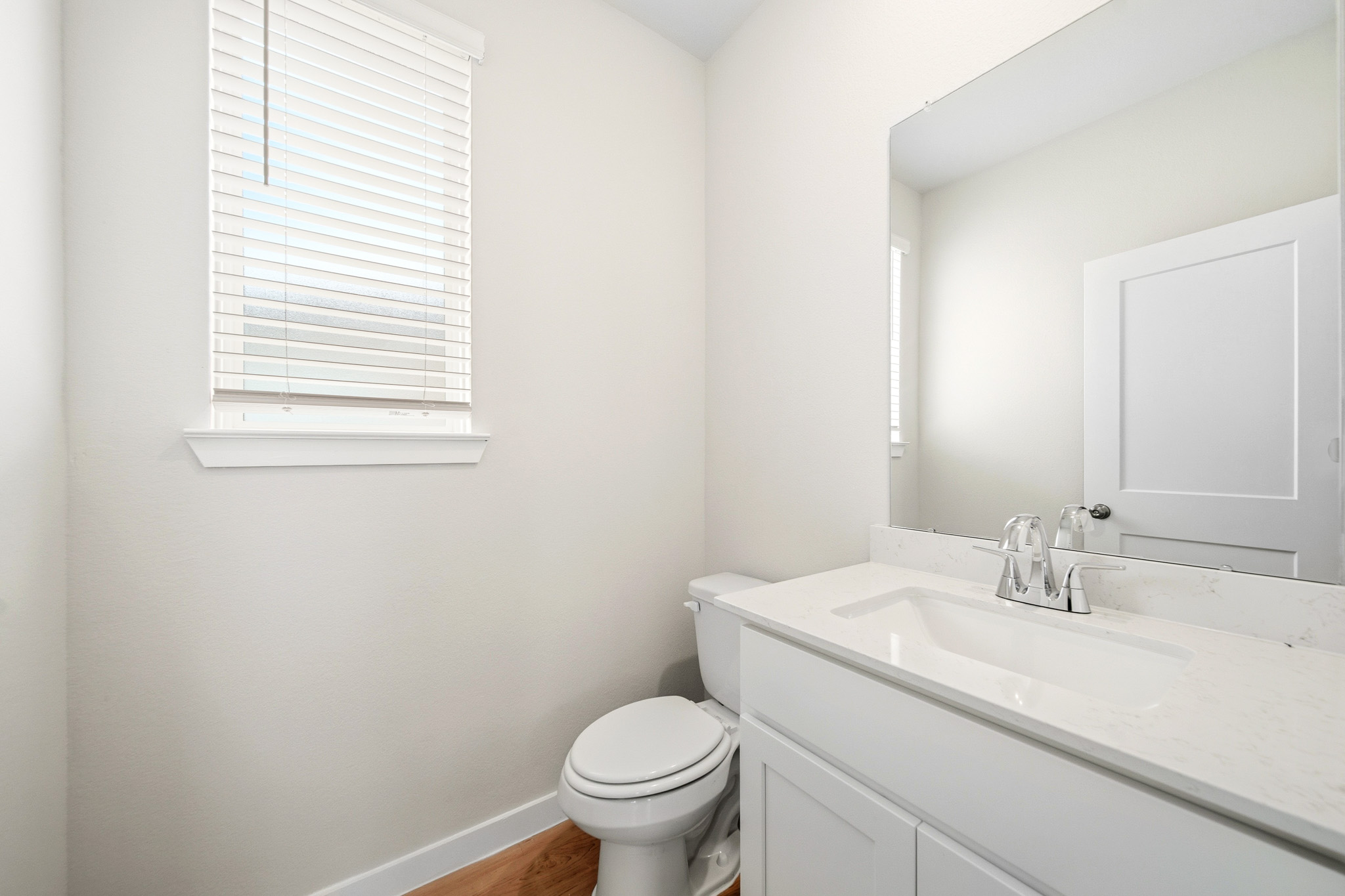 A bathroom with a toilet sink and a mirror.