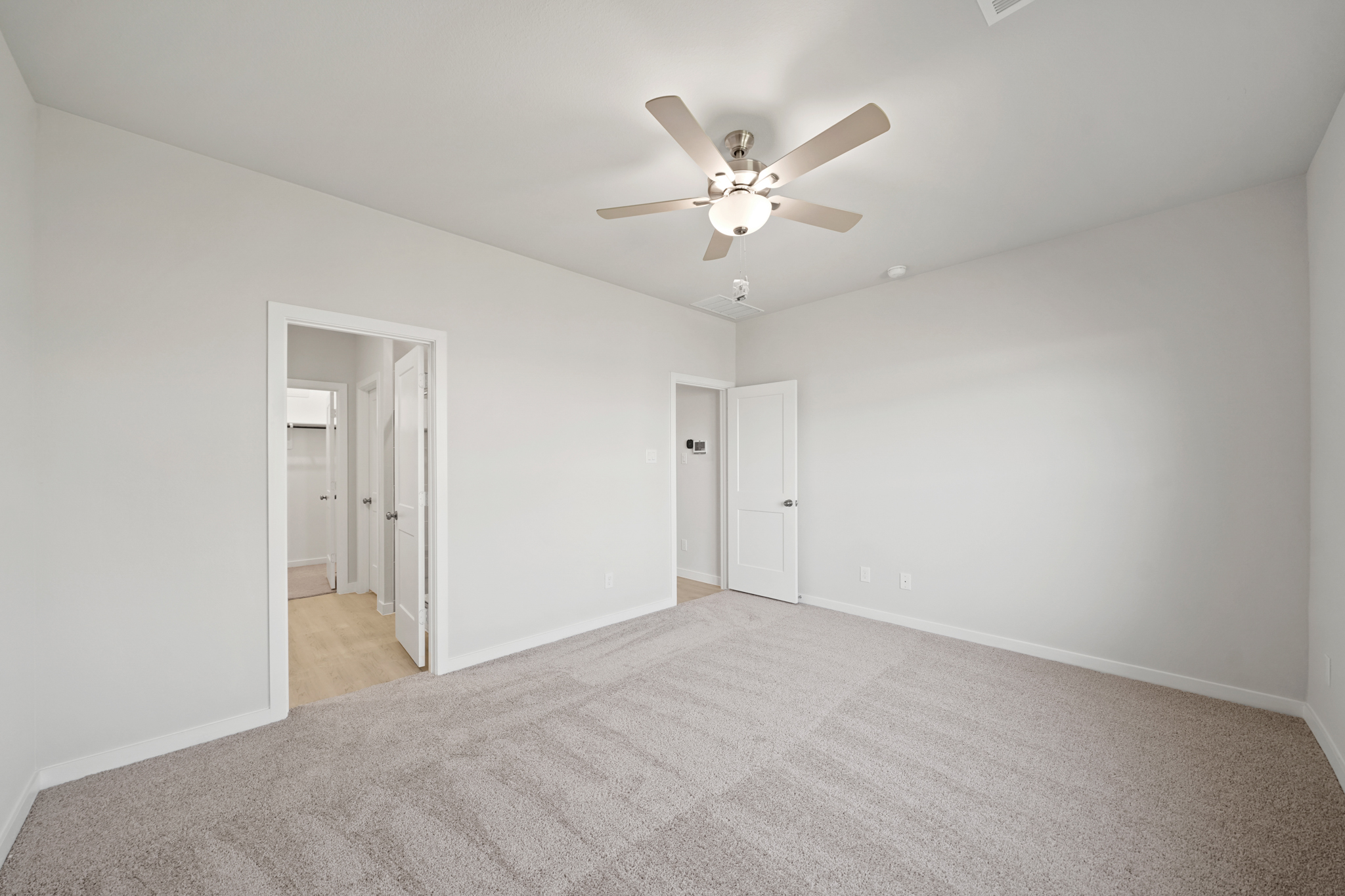 A room with a ceiling fan and a carpet.