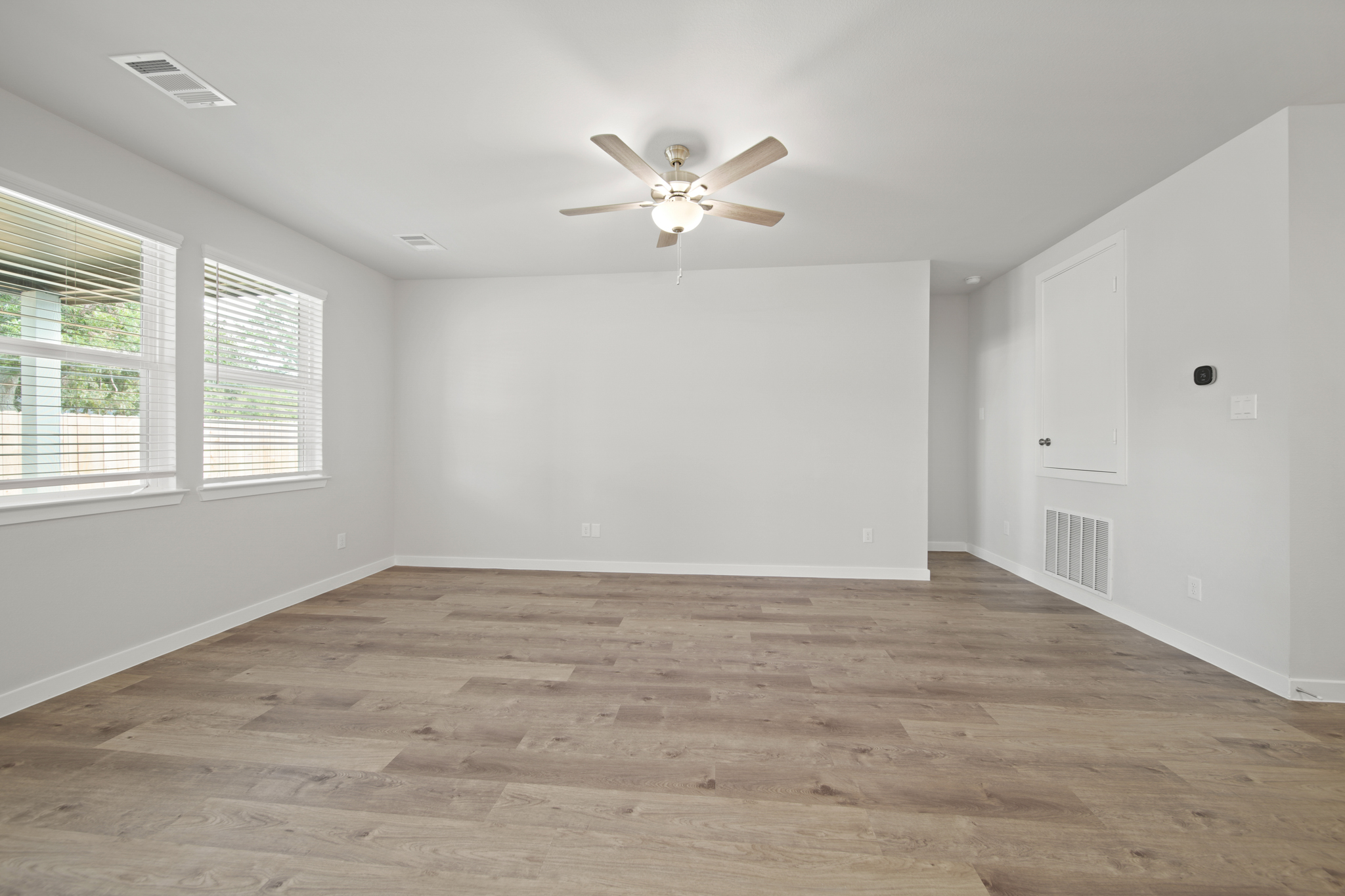 A room with a ceiling fan and a wood floor.