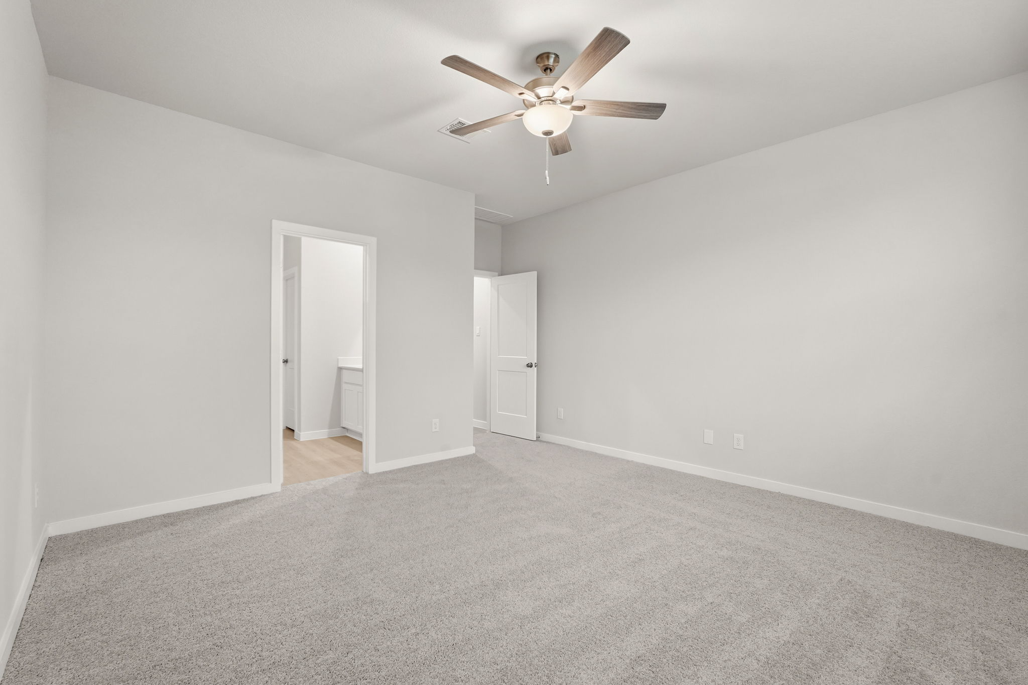 A room with a ceiling fan and a door.
