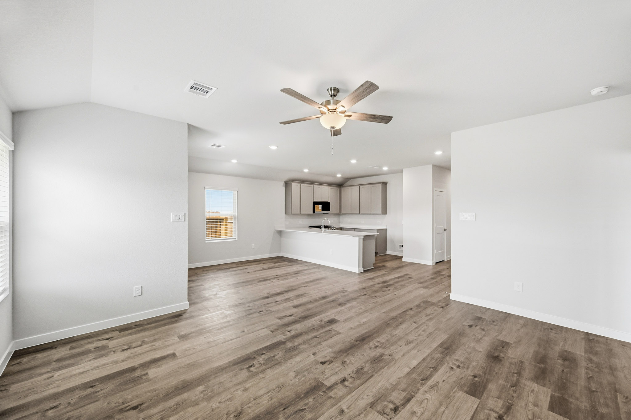 A large empty room with a wood floor and a ceiling fan.