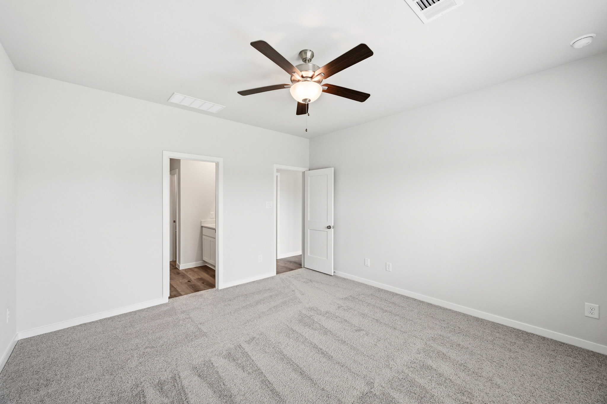 A room with a ceiling fan and a carpet.