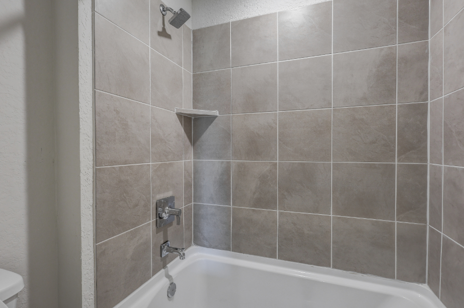 A bathtub with a tile wall.