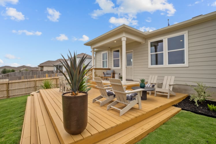 A deck with chairs and a table on it next to a house.
