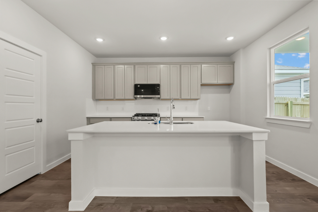 A white kitchen with a white counter top and white cabinets.