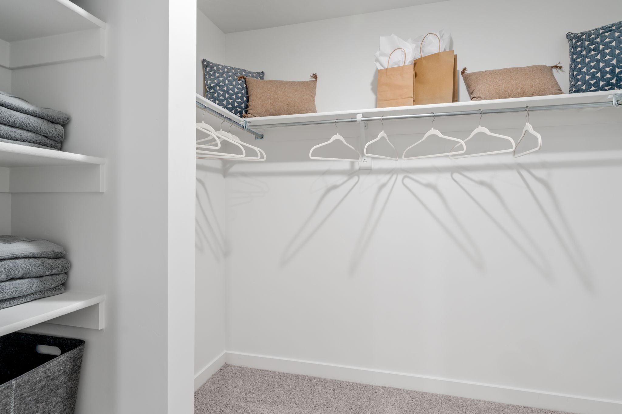 A white shelf with towels and pillows.